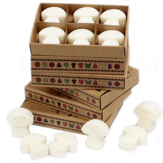 Mushroom-shaped wax melts are arranged in a stack of boxes decorated with a repeating pattern of small icons.  The boxes sit on a white surface. Several additional wax melts are scattered nearby.