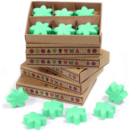 Mint-colored wax melts, shaped like flowers, are contained in and stacked on top of several decorated cardboard boxes.