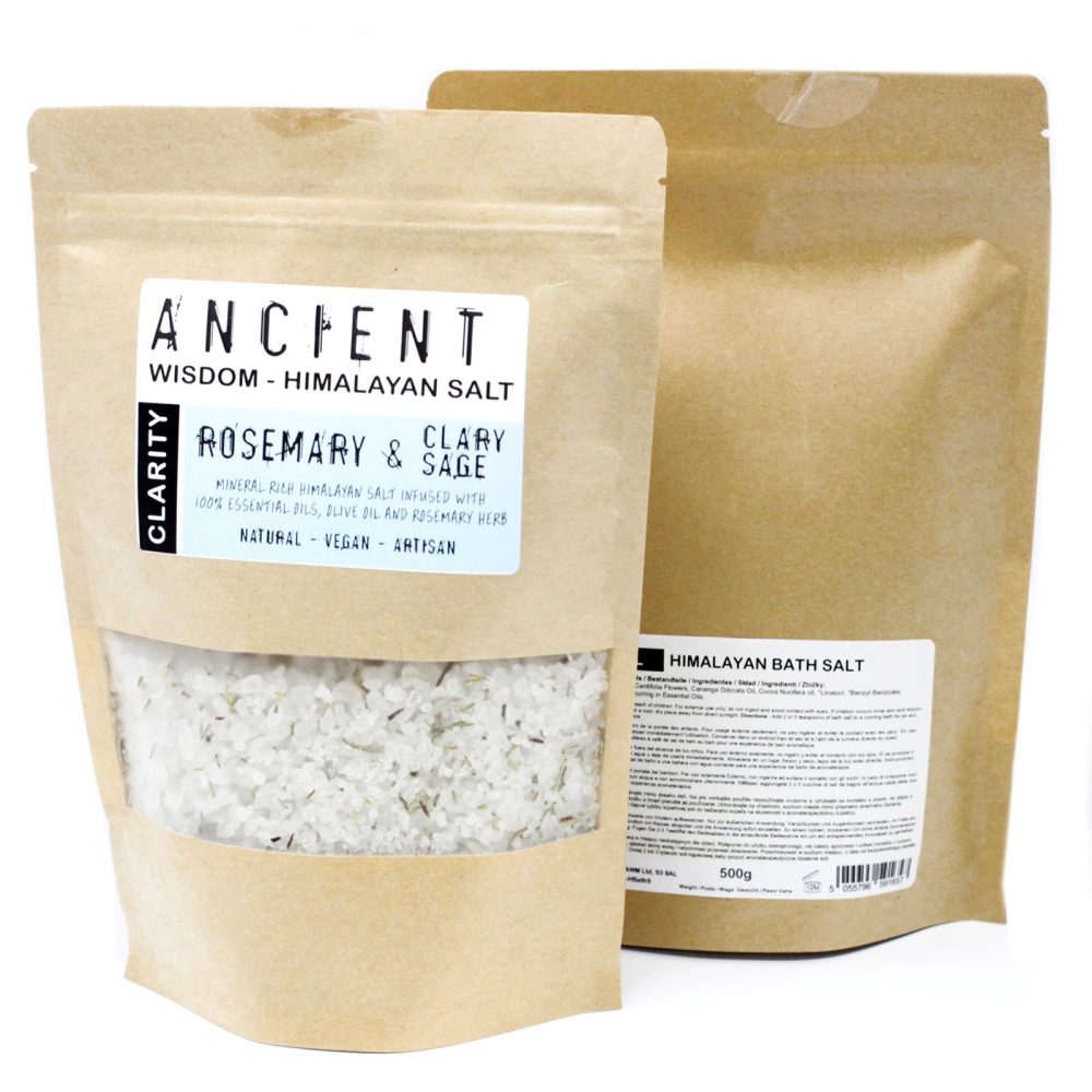 Two brown paper packages advertise bath salts. The package in the front says "ANCIENT WISDOM - HIMALAYAN SALT CLARITY ROSEMARY & CLARY SAGE MINERAL RICH HIMALAYAN SALT INFUSED WITH 100% ESSENTIAL OILS, OLIVE OIL AND ROSEMARY HERB NATURAL - VEGAN - ARTISAN." The package in the background says "HIMALAYAN BATH SALT 500g 5055796".