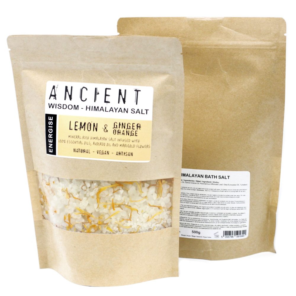 Two stand-up kraft bags show salt. The front bag reads "ANCIENT WISDOM - HIMALAYAN SALT", "LEMON & GINGER ORANGE" and "NATURAL - VEGAN - ARTISAN". It is transparent at the bottom, revealing salt with yellow bits. The other bag reads "IMALAYAN BATH SALT" and "500g".