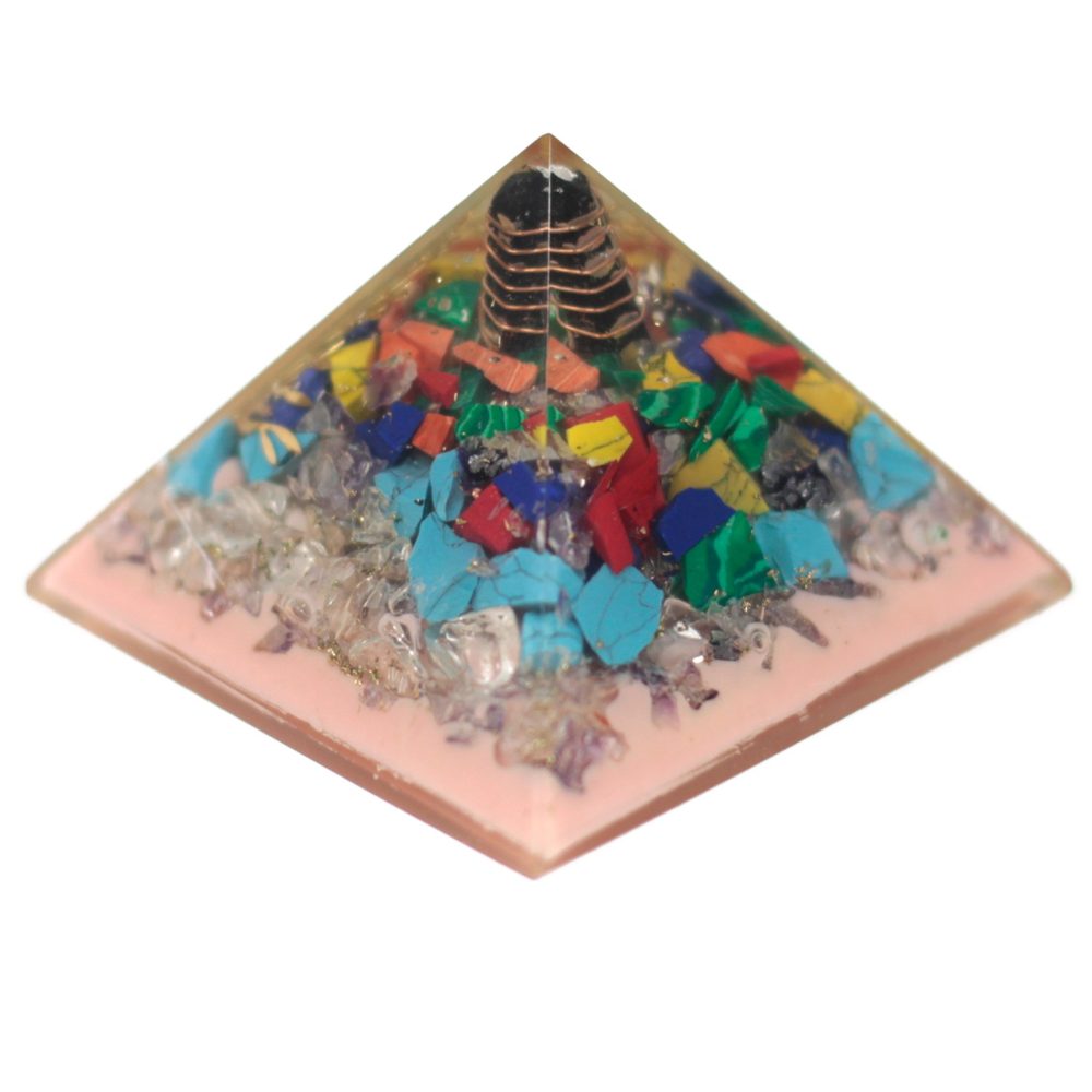 A pyramid sits against a white backdrop. The base of the pyramid is pink and filled with stones, colored gems, and a copper coil with a black tip at the top.