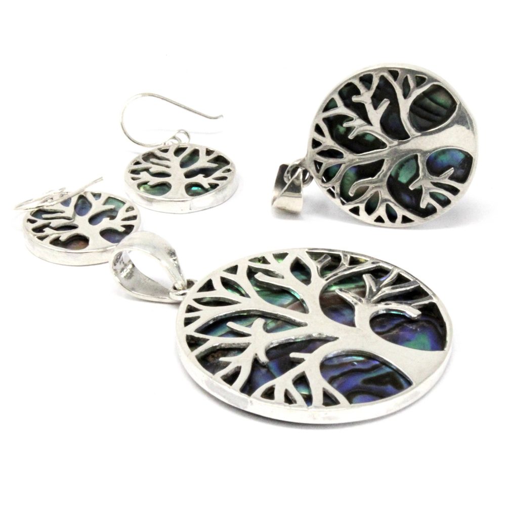 Jewelry set is displayed: two earrings and two pendants. The design features a silver tree silhouette with a shimmering, blue and green abalone shell background, set against a white background.