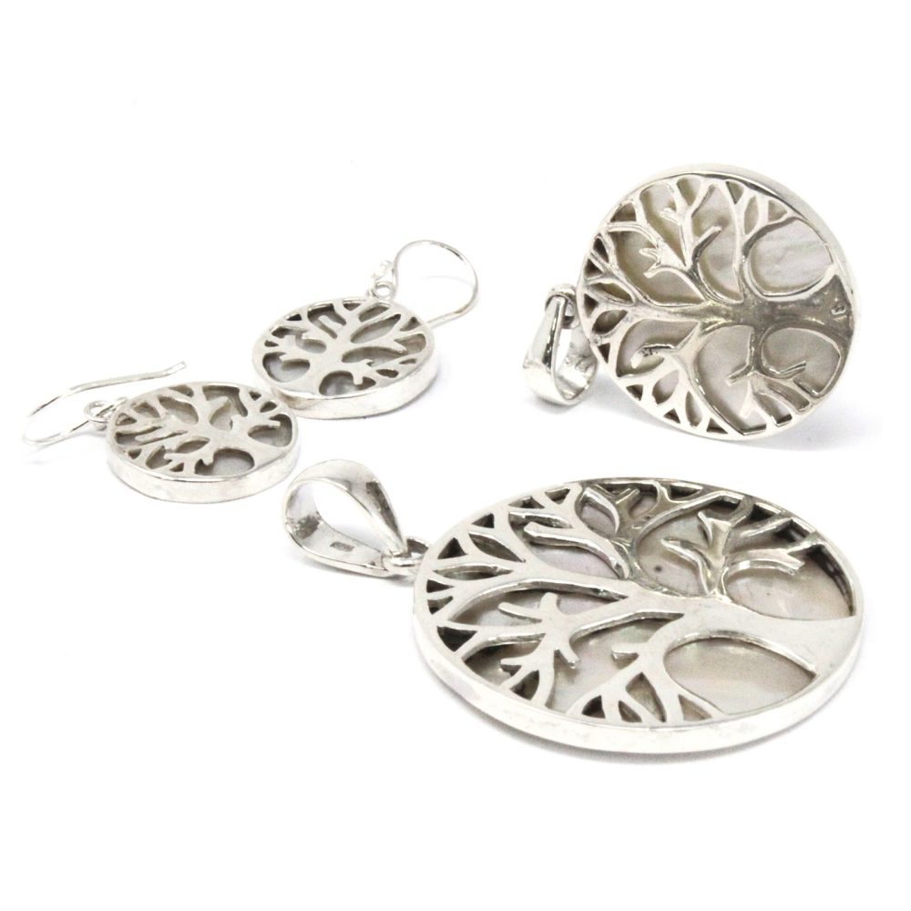 Jewelry is displayed on a white background. Silver pendants and earrings feature a cut-out tree-of-life design over a pearly white disc.