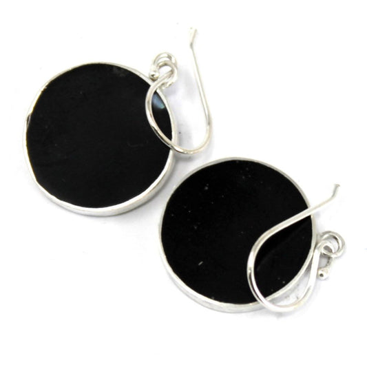 Two round, black stone earrings with silver-colored rims and earring hooks rest against a white background.