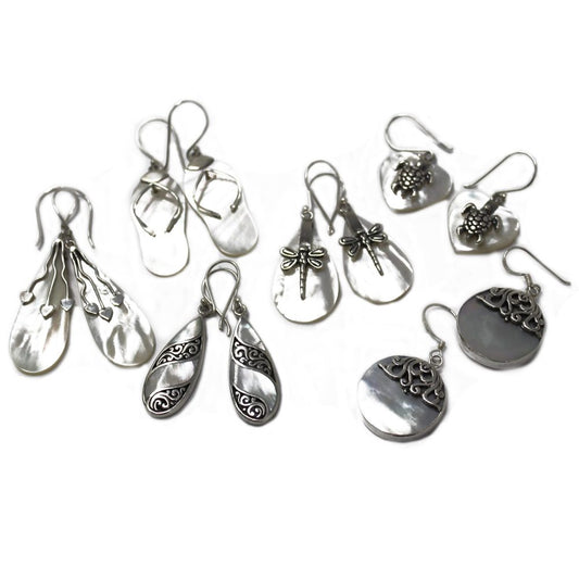 Various pairs of white, shiny earrings, some with silver charms and designs, are displayed on a stark white surface.