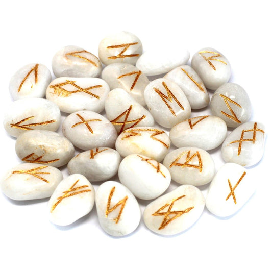 White, smooth stones display gold-colored rune symbols. The stones are scattered in a group against a plain white background.