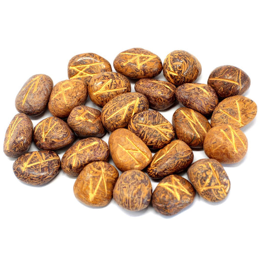 A pile of roughly oval, brown, stone-like objects, each with a single, light-brown angular glyph inscribed on it, lies scattered against a white background.