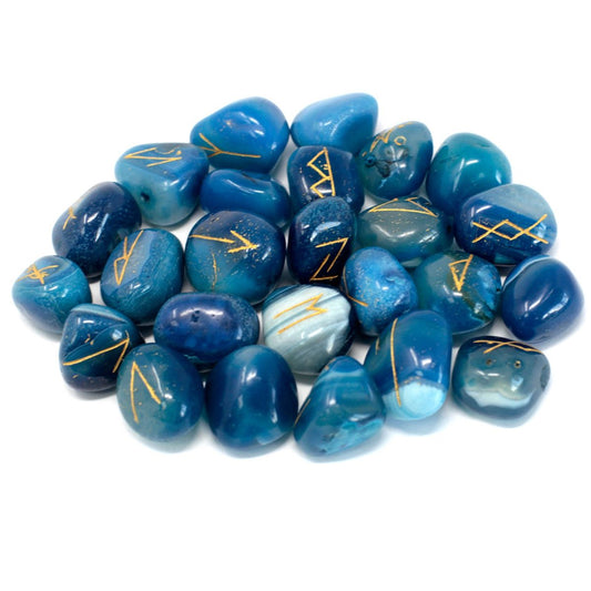 A pile of smooth, blue, tumbled stones displaying gold-colored, rune-like symbols sits on a white surface.