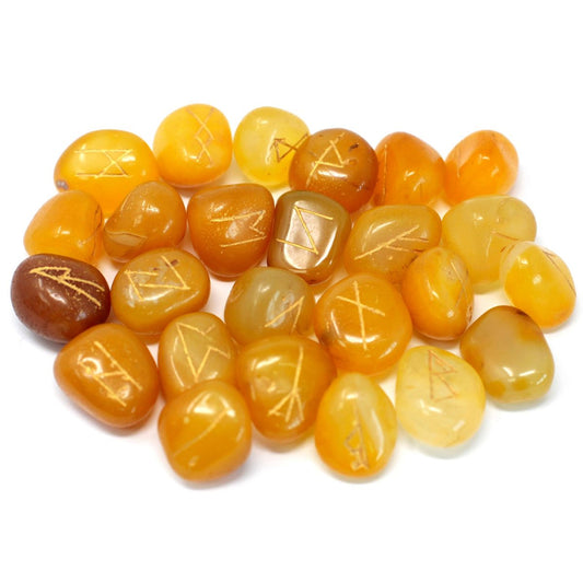 Several orange tumbled stones are scattered on a white surface; each stone has a golden rune etched on it.