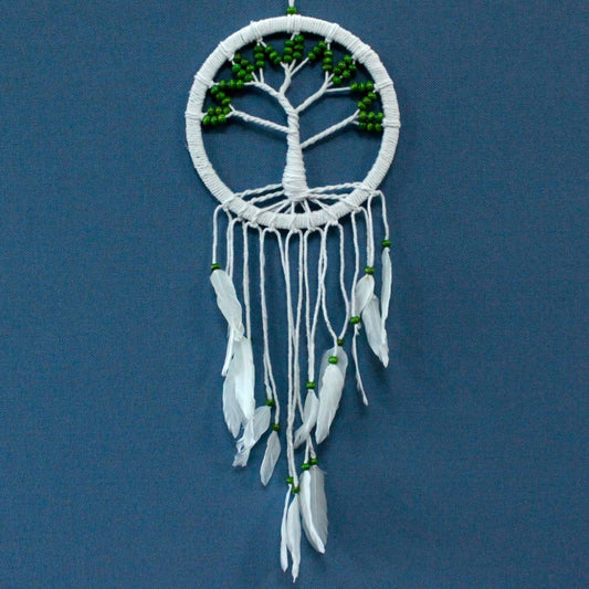 A dreamcatcher, featuring a beaded tree of life design, hangs against a blue background. White feathers and green beads adorn the bottom.