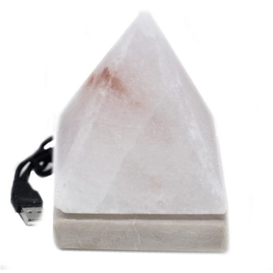 A pyramid-shaped salt lamp sits on a base, connected to a USB cable. The lamp is pale with reddish hues, placed against a plain, white background.