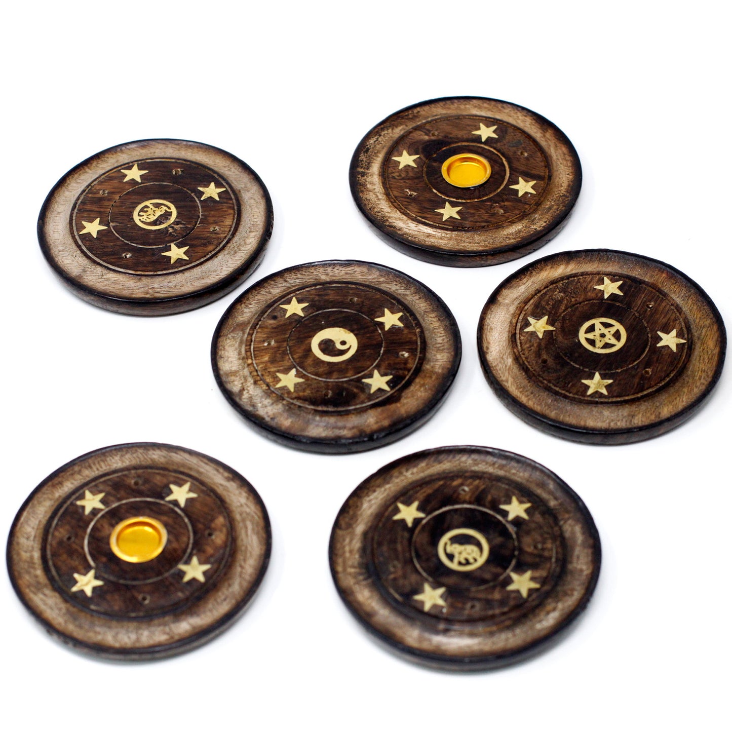 Wooden discs feature engraved symbols, including a yin yang, pentacle, and celestial motifs, with small stars around each. They are arranged in a group on a white surface.