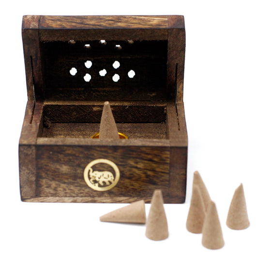 Wooden incense box with an open lid displays a burning cone. Six additional cones are nearby. Context features decorative holes and an elephant design on the box front.