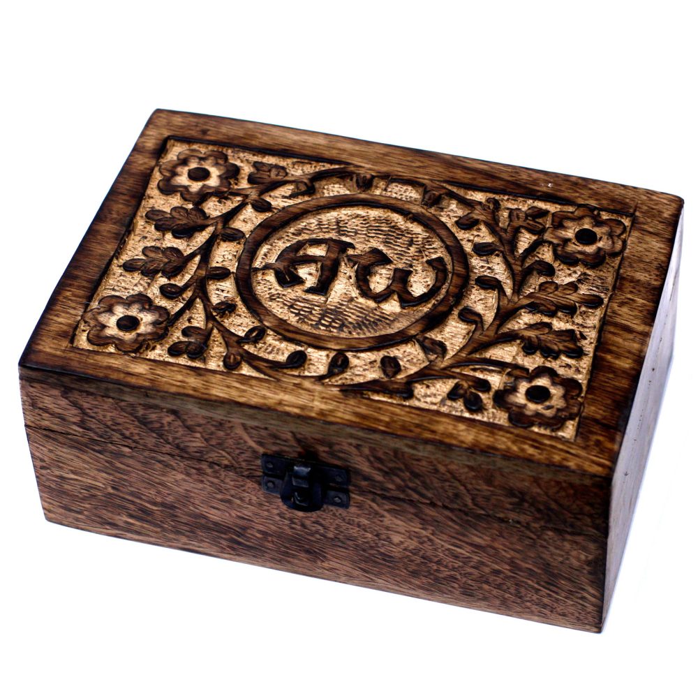 A rectangular wooden box has a floral design carved into its lid, which also features the letters "AW" in a circle at the center. The box is on a white surface.