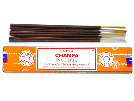 Incense sticks are lined above an orange box labeled "SATYA CHAMPA INCENSE," with "EXPORT QUALITY" and "NET. W.T. 15g" visible, produced by Shrinivas Sugandhalaya in Bengaluru, India.
