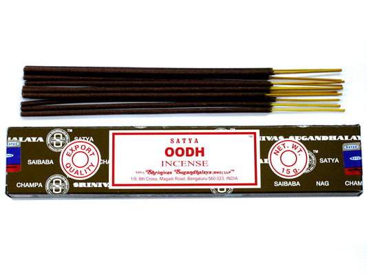 Incense sticks lie on a box labeled "Satya Oodh Incense," marked with "Export Quality" and "Net Wt. 15g." Manufactured by Shrinivas Sugandhalaya, located at Magadi Road, Bengaluru, India.