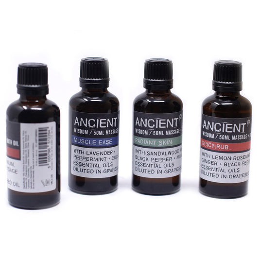 Four small, dark brown bottles labeled "ANCIENT Wisdom/50ML MASSAGE" sit in a row on a white surface. The labels list different massage oil blends: "MUSCLE EASE," "RADIANT SKIN," and "SPICY RUB," along with their ingredients and base.