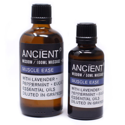 Two amber glass bottles, one labeled "ANCIENT" "WISDOM / 100ML MASSAGE +" "MUSCLE EASE" "WITH LAVENDER + PEPPERMINT + EUCAL ESSENTIAL OILS DILUTED IN GRAPESE" and the other labeled "ANCIENT" "WISDOM / 50ML MASSAGE" "MUSCLE EASE" "WITH LAVENDER + PEPPERMINT + EUC ESSENTIAL OILS DILUTED IN GRAPES", stand on a white surface.