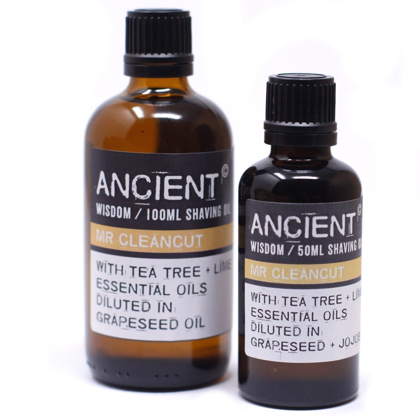 Two brown glass bottles stand side-by-side on a white surface. Both display the label "ANCIENT WISDOM / (volume) SHAVING OIL MR CLEANCUT WITH TEA TREE + LIME ESSENTIAL OILS DILUTED IN GRAPESEED (or + JOJO) OIL”.