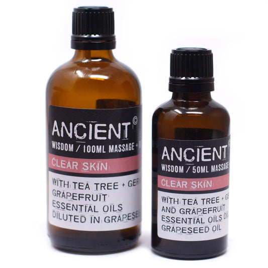 Two amber bottles of essential oils sit on a white background. The bottles have black labels with white text that reads: "ANCIENT WISDOM / 100ML MASSAGE + CLEAR SKIN WITH TEA TREE + GER GRAPEFRUIT ESSENTIAL OILS DILUTED IN GRAPESEED"; "ANCIENT WISDOM / 50ML MASSAGE CLEAR SKIN WITH TEA TREE + G AND GRAPEFRUIT ESSENTIAL OILS GRAPESEED OIL."