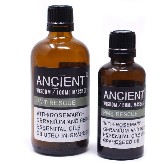 Two amber bottles stand on a white surface. The larger bottle on the left reads "ANCIENT WISDOM / 100ML MASSAGE PMT RESCUE WITH ROSEMARY + GERANIUM AND BERG ESSENTIAL OILS DILUTED IN GRAPESE". The smaller bottle on the right reads "ANCIENT WISDOM / 50ML MASSAGE PMS RESCUE WITH ROSEMARY + GERANIUM AND BER ESSENTIAL OILS DIL GRAPESEED OIL".