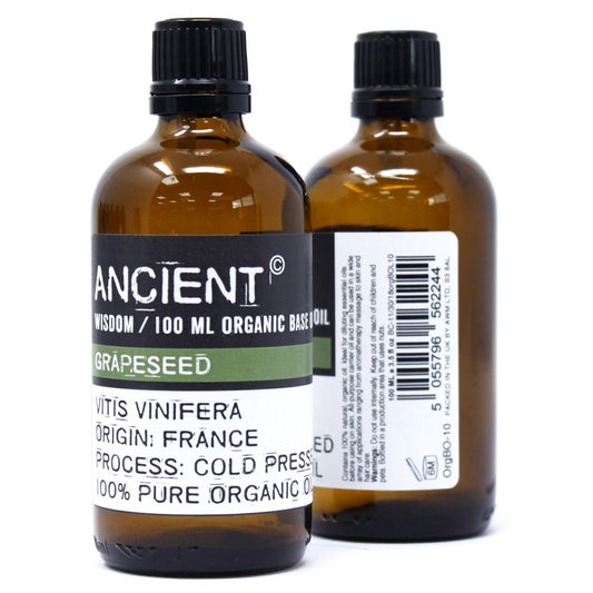 Two brown bottles of "ANCIENT" brand 100 ML Organic Base Oil stand against a white background. The front bottle's label reads GRAPESEED, VITIS VINIFERA, ORIGIN: FRANCE, and PROCESS: COLD PRESS.