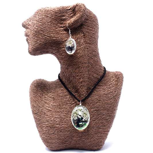 A twine mannequin wears an oval pendant necklace with a miniature tree inside its transparent casing, and a matching earring, against a white background.