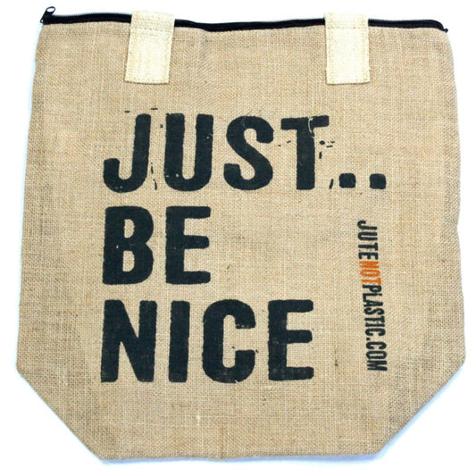 A tan jute bag sits against a white backdrop, imprinted with the vertically stacked text "JUST... BE NICE" in black and "JUTE NOT PLASTIC.COM" in orange on the right. The bag has a black zipper and two white handles.