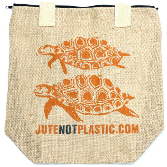 Jute tote bag displays two orange turtle drawings above the text "JUTENOTPLASTIC.COM" near the bottom of the bag.