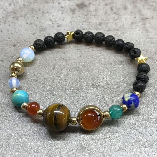 A beaded bracelet, featuring star accents and round stones of varying colors and textures, sits on a gray surface.
