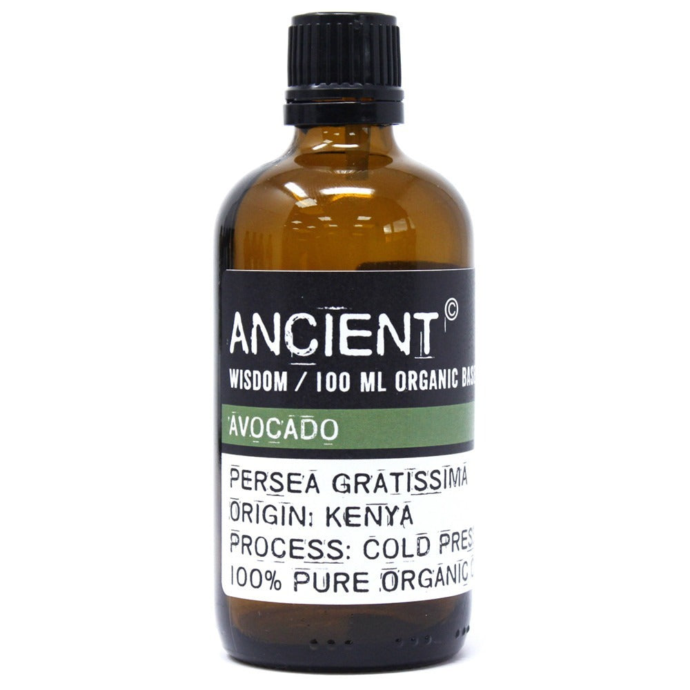 An amber glass bottle with a black cap sits on a white surface. It features a label that reads "ANCIENT WISDOM / 100 ML ORGANIC BAS AVOCADO PERSEA GRATISSIMA ORIGIN: KENYA PROCESS: COLD PRES 100% PURE ORGANIC".