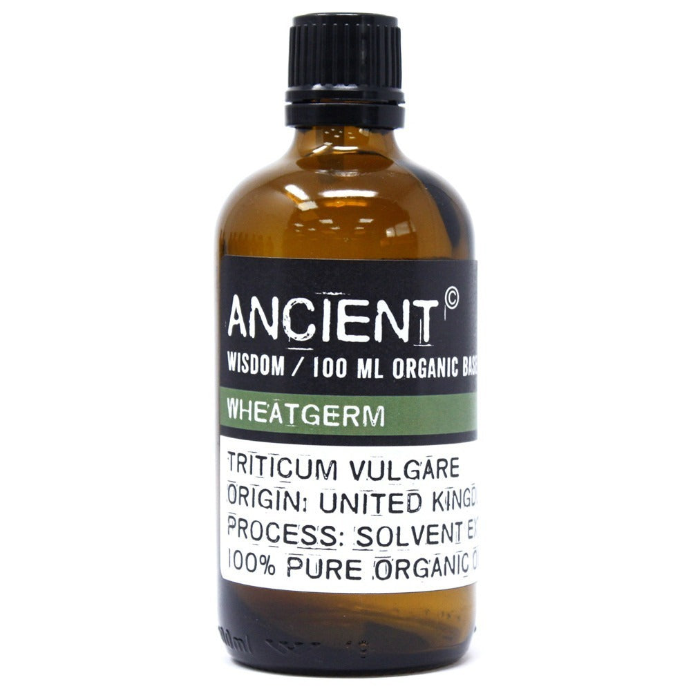 A brown glass bottle labeled "ANCIENT" "WISDOM / 100 ML ORGANIC BAS" "WHEATGERM" "TRITICUM VULGARE" "ORIGIN: UNITED KINGD" "PROCESS: SOLVENT E" and "100% PURE ORGANIC" sits on a white surface.