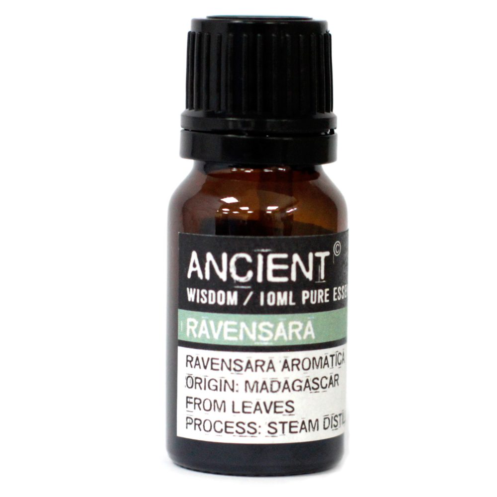 An amber bottle stands on a white surface; it has a black, ribbed cap and a label reading, "ANCIENT WISDOM / 10ML PURE ESSE RAVENSARA RAVENSARA AROMATICA ORIGIN: MADAGASCAR FROM LEAVES PROCESS: STEAM DIST".
