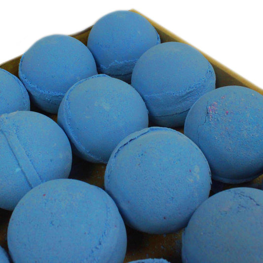 Blue, spherical bath bombs are arranged neatly in a cardboard tray. Their smooth surfaces display slight cracks and imperfections, suggesting a handmade quality within a simple, minimalist setting.
