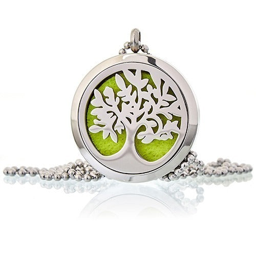 A silver locket pendant featuring a cut-out tree of life design hangs from a ball chain. The pendant has a lime green felt pad inside.