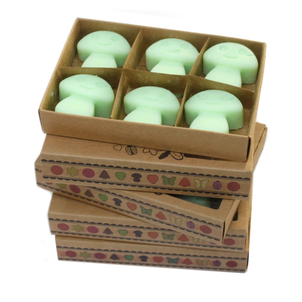 Six light green mushroom-shaped wax melts are contained within a cardboard box.  A stack of similar boxes sits below.