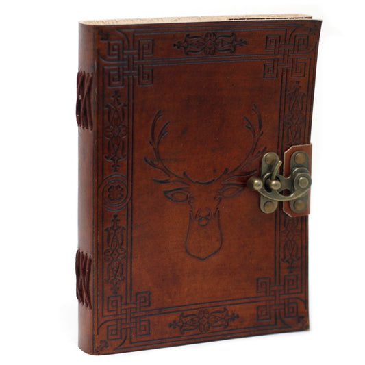 A brown leather journal, featuring a deer's head embossed on the front cover and a metallic clasp, stands on a white surface. Border designs accent the cover and spine.