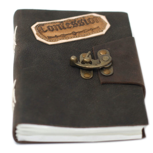 A brown leather-bound journal with a brass clasp rests on a white surface. The cover has a decorative patch reading "Confession."