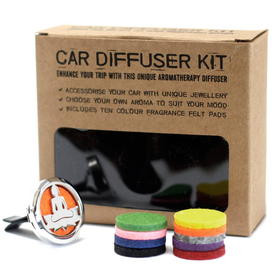 A car diffuser kit sits near two small stacks of colored felt pads on a white surface. The box reads "CAR DIFFUSER KIT ENHANCE YOUR TRIP WITH THIS UNIQUE AROMATHERAPY DIFFUSER * ACCESSORISE YOUR CAR WITH UNIQUE JEWELLERY * CHOOSE YOUR OWN AROMA TO SUIT YOUR MOOD * INCLUDES TEN COLOUR FRAGRANCE FELT PAD'S"