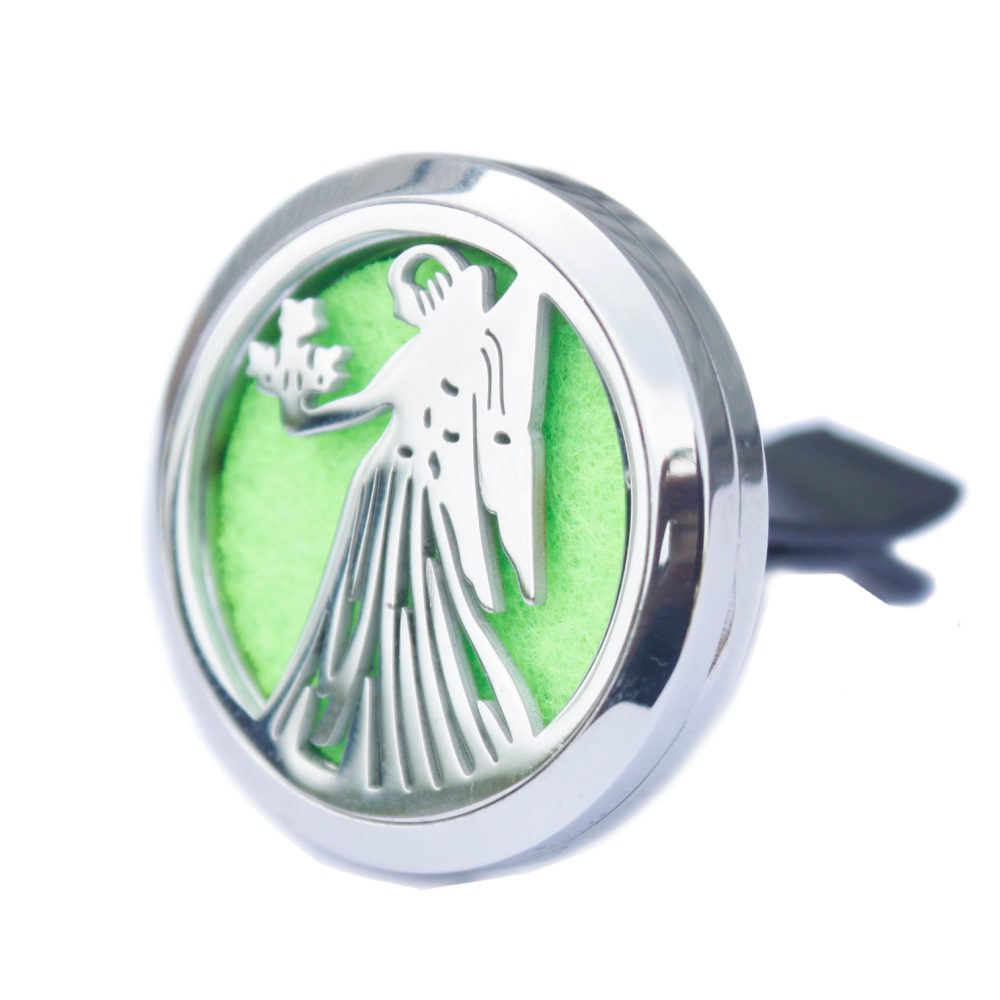 A silver circular car vent clip displays an angel holding flowers against a green felt backing. Black prongs for vent attachment protrude from the back.