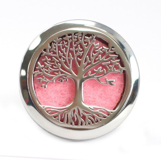 A silver tree of life locket rests on a white background. The design is cut out, revealing a pink pad underneath.