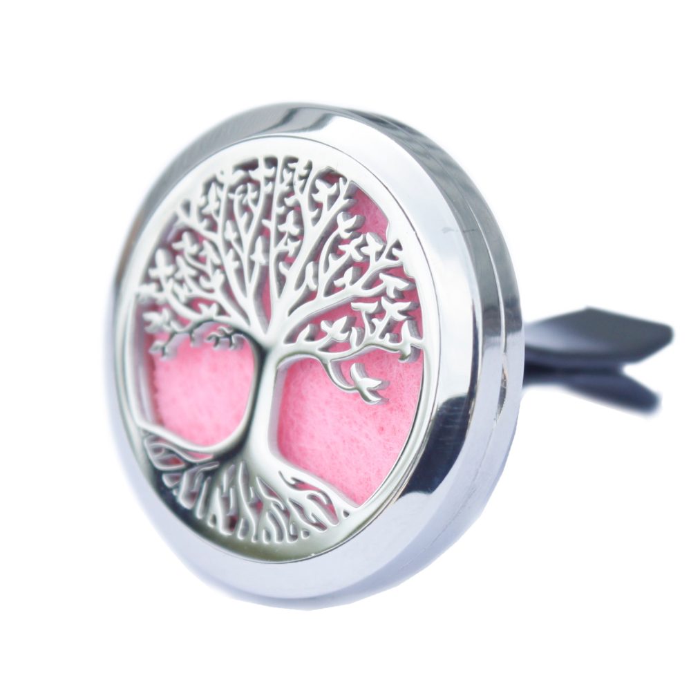 A circular, silver aromatherapy diffuser featuring a tree-of-life cutout displays a pink insert. The back has an attachment for clipping onto a car vent, on a white background.