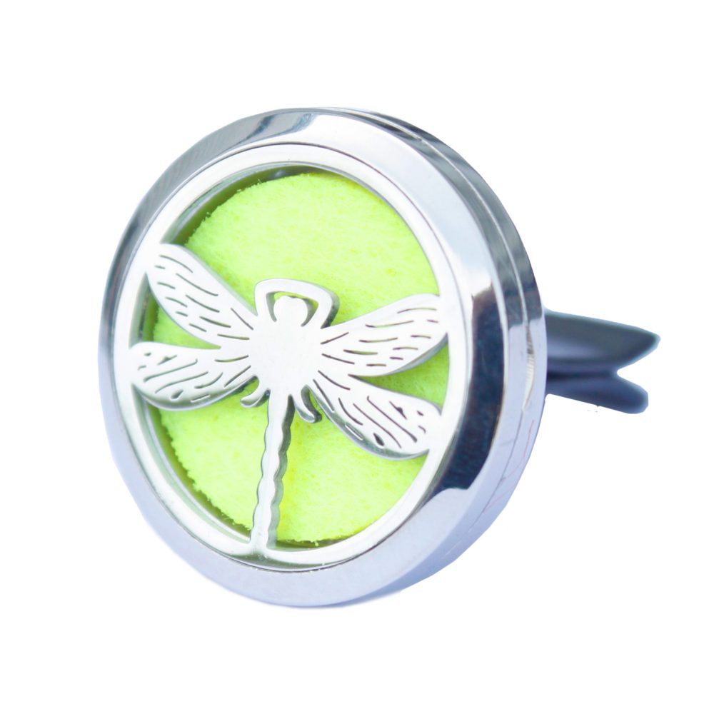 A silver dragonfly rests in a round, silver car diffuser with a bright yellow filter. The diffuser has a clip on the back.