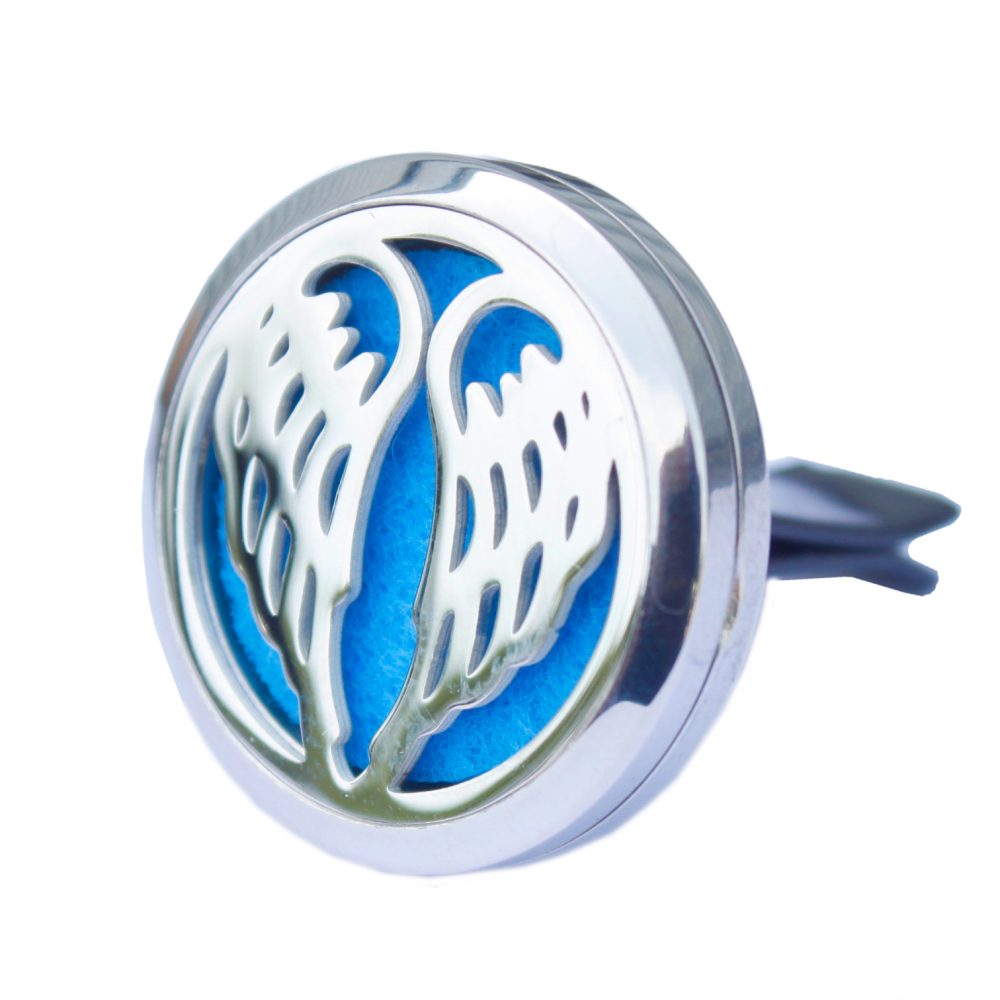 A circular, silver car vent air freshener displays angel wings cutouts on a blue felt background and has a vent clip attached.