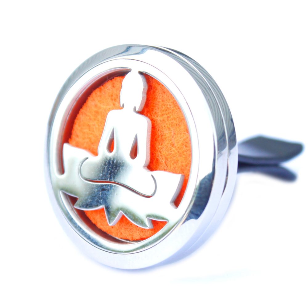 A chrome, circular car freshener displays a cutout of the Buddha in lotus position, which reveals an orange felt insert, against a white backdrop.