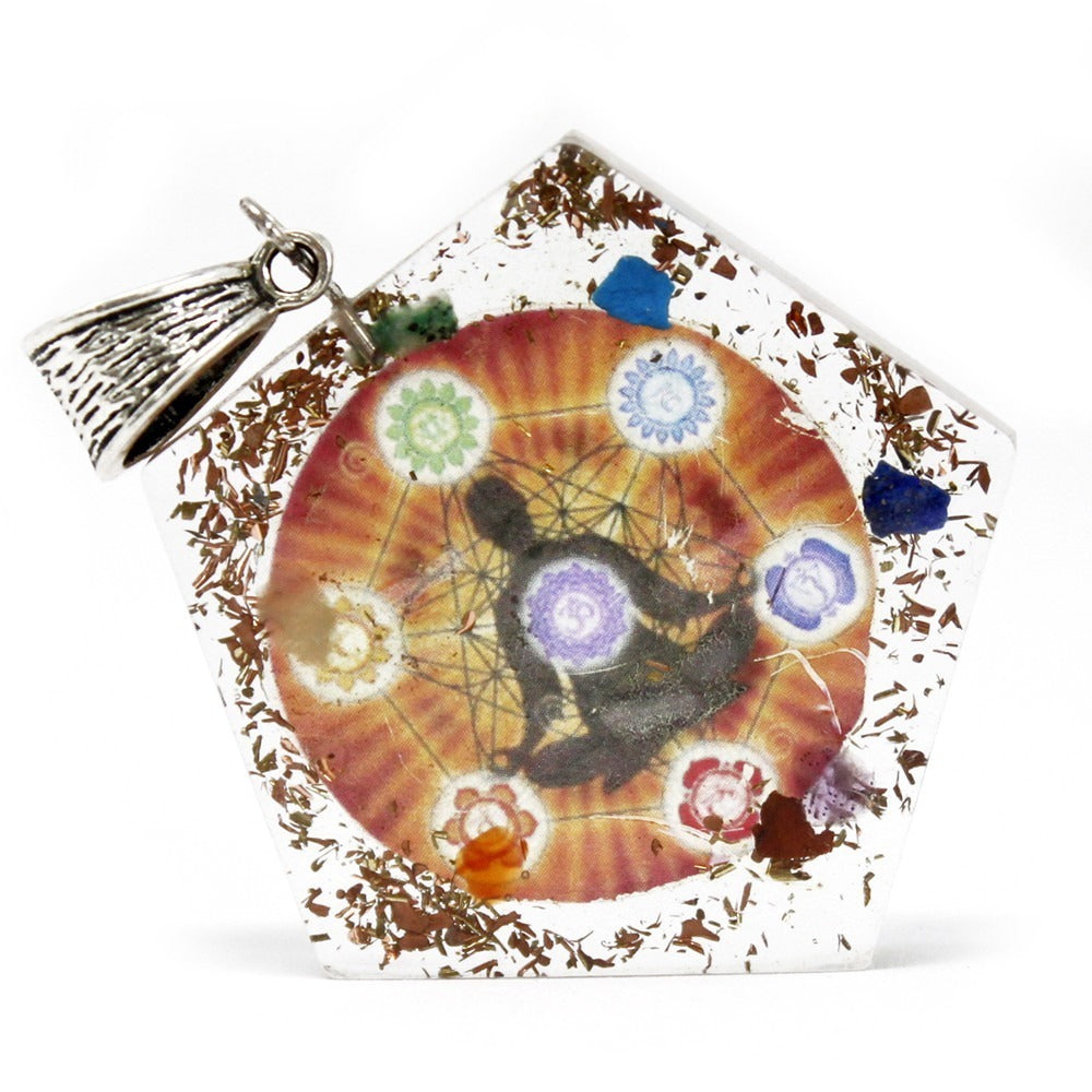 A pentagon-shaped orgonite pendant is displayed, featuring a seated silhouette surrounded by chakra symbols on a red gradient backdrop, embedded with crystals and metal shavings. A silver bail is attached.