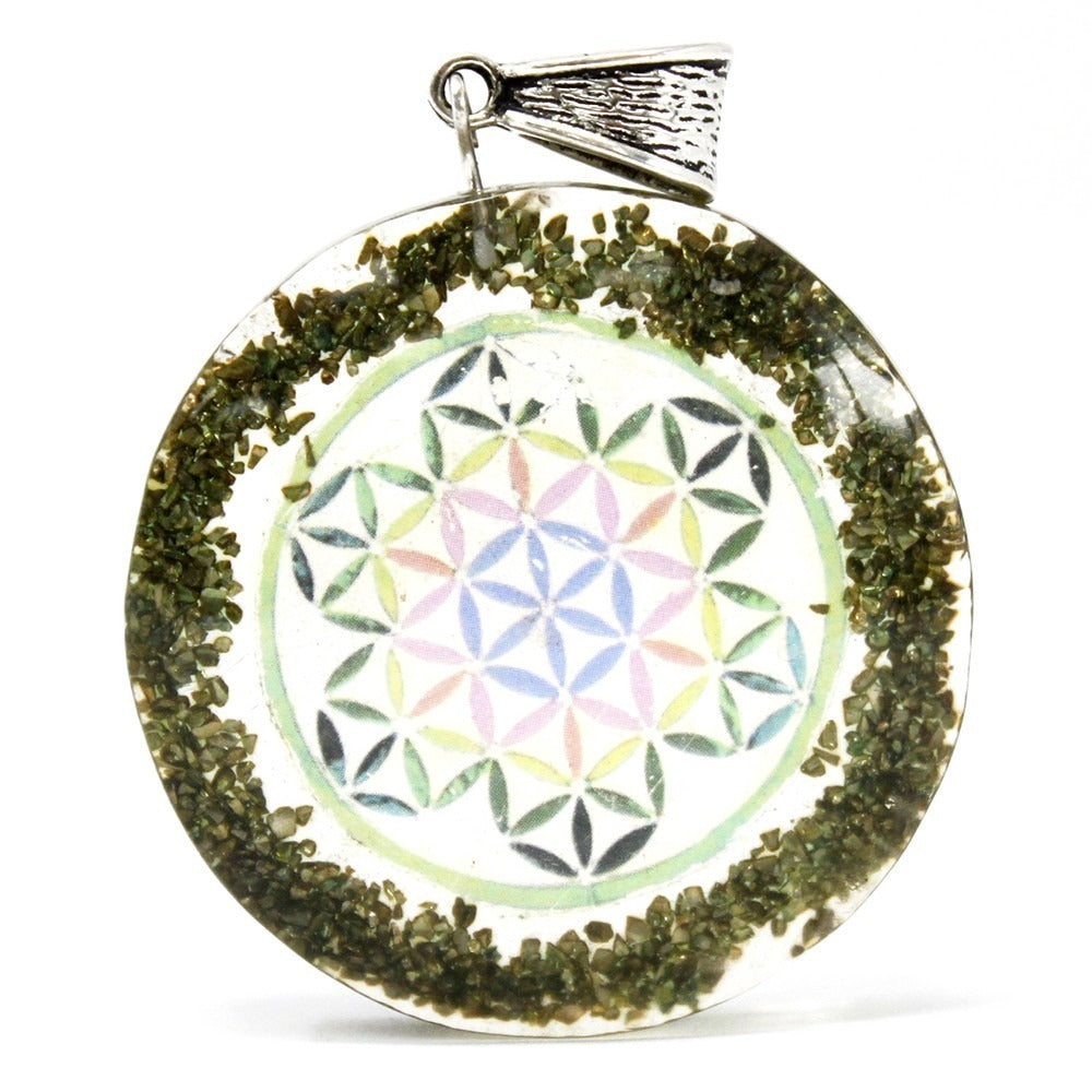 A round pendant features a "flower of life" design in pastels encased in clear resin, surrounded by dark green granules, and has a metal loop at the top.