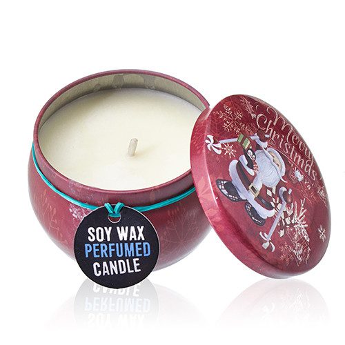 Red tin candle sits open with lid beside it on a white surface, showing a wick and a hanging tag reading SOY WAX PERFUMED CANDLE and lid printed Merry Christmas.