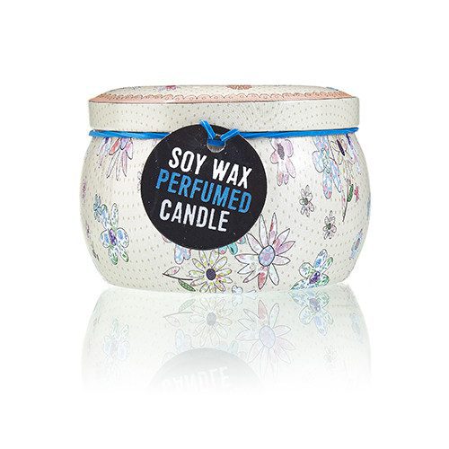 Decorative round soy wax candle jar sits on a white reflective surface, displaying a black tag reading: SOY WAX PERFUMED CANDLE; cream jar patterned with pastel flowers.