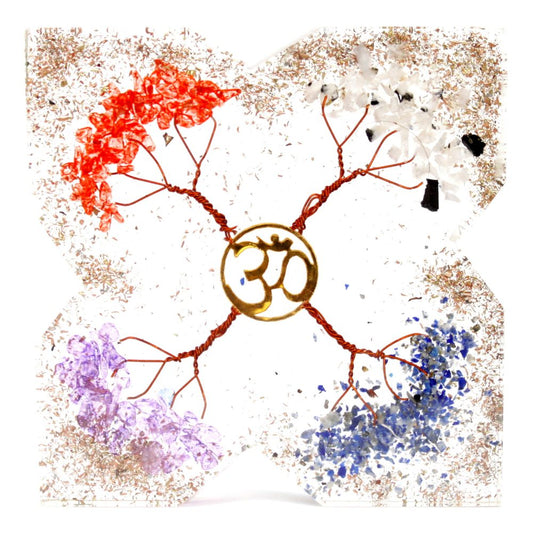 An om symbol is at the center of a square object. Four branches with colored crystals (red, white, purple, blue) extend out from the om across a speckled, light-colored surface.